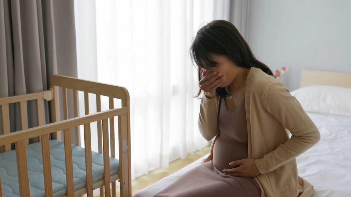 Pregnant person experiencing nausea while sitting, representing hyperemesis gravidarum medical research breakthrough