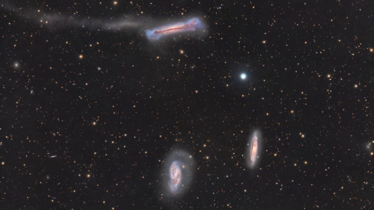 Detailed space photograph showing three spiral galaxies of the Leo Triplet against deep space