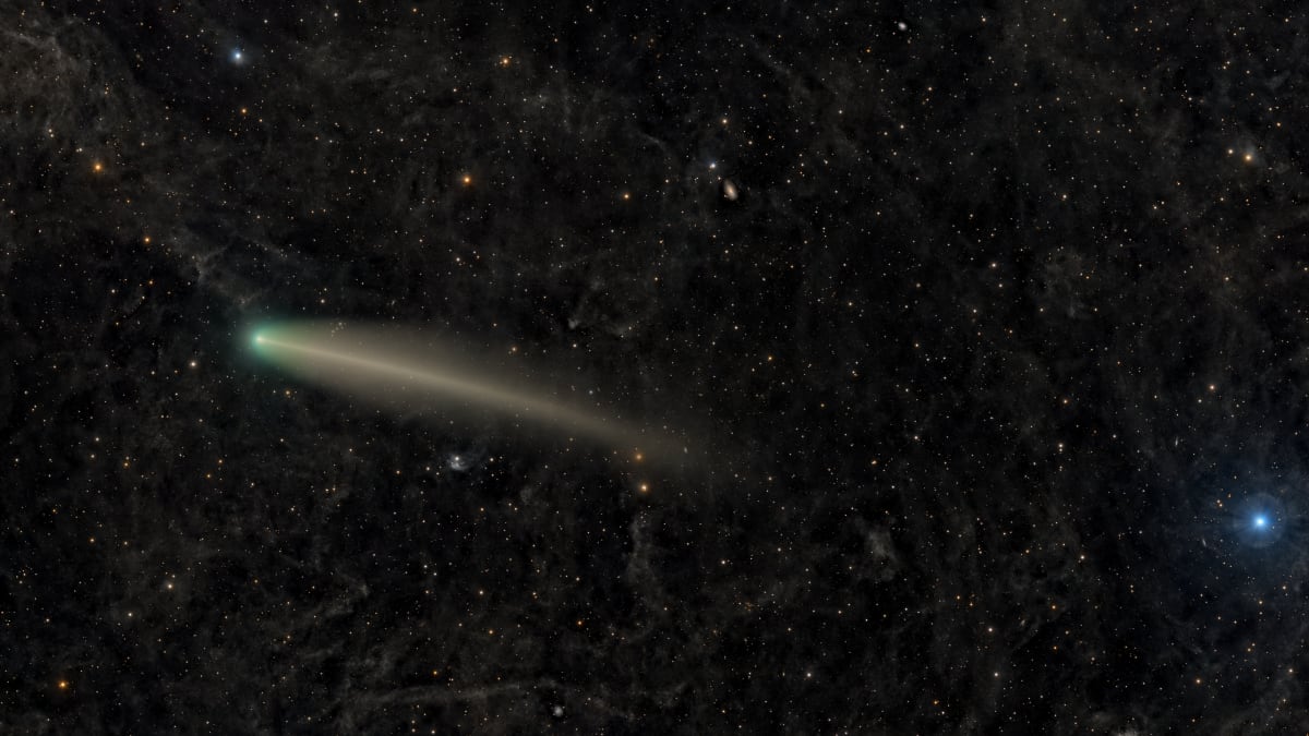 ** Comet McNaught glowing with bright tail against starry night sky over California landscape