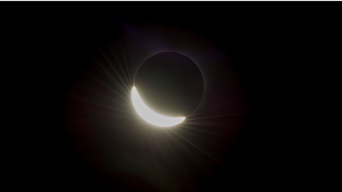 Total solar eclipse showing sun's corona glowing around moon's dark silhouette against black sky