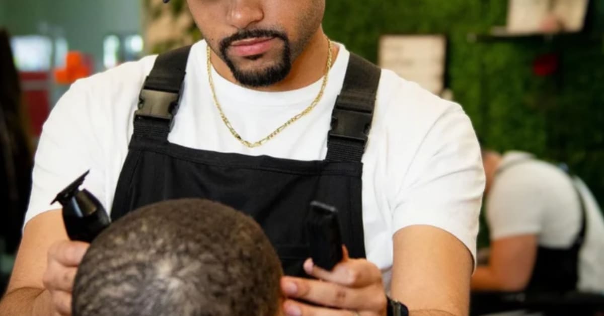 Barber Henry Amoloja giving a haircut to a young child in his sensory-friendly Dallas barbershop