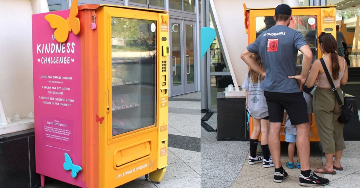 Colorful vending machine with kindness challenge envelopes visible through glass display window