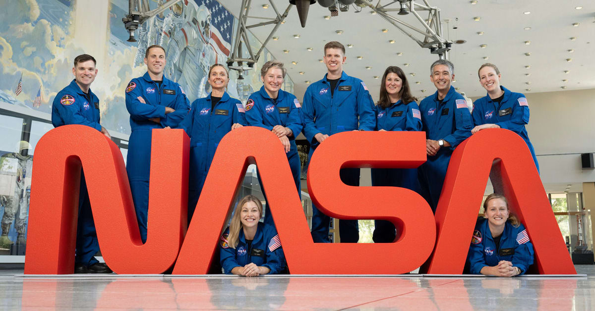 NASA astronaut Christina Koch in orange flight suit smiling at camera