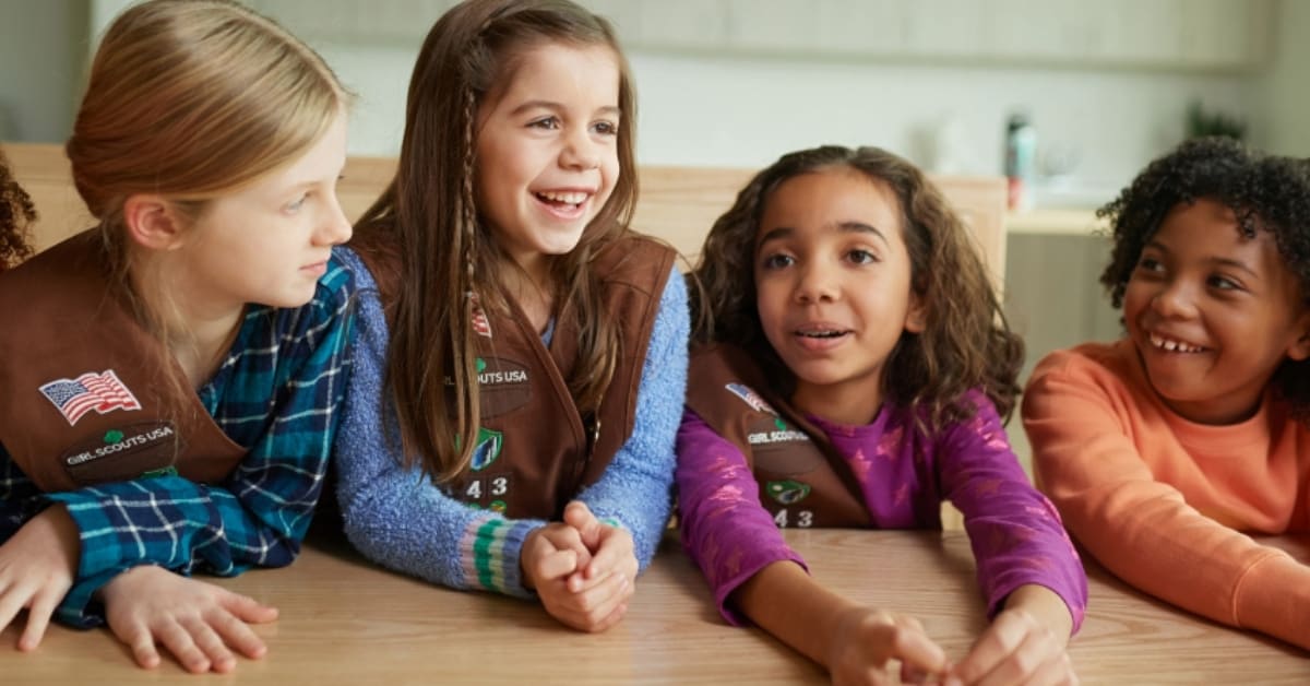 Diverse group of young Girl Scouts in uniform smiling together outdoors during troop activity