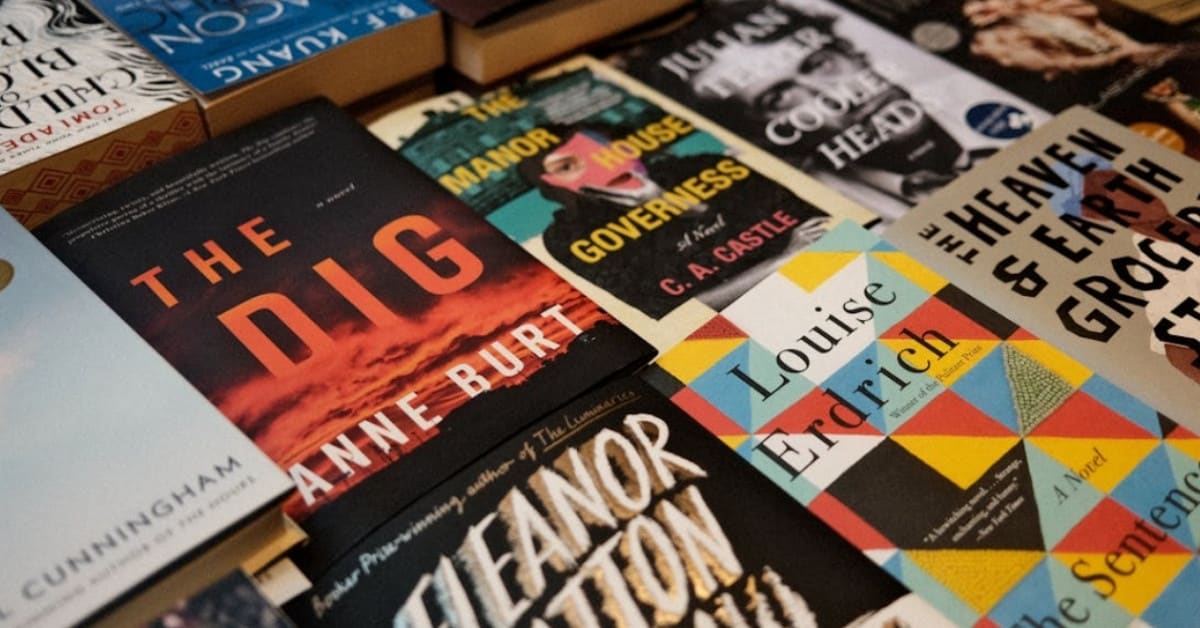Person browsing colorful book spines on wooden shelves in bright modern bookstore