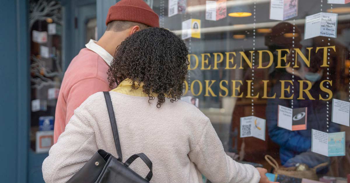 Customers browsing books inside a cozy independent bookstore with wooden shelves