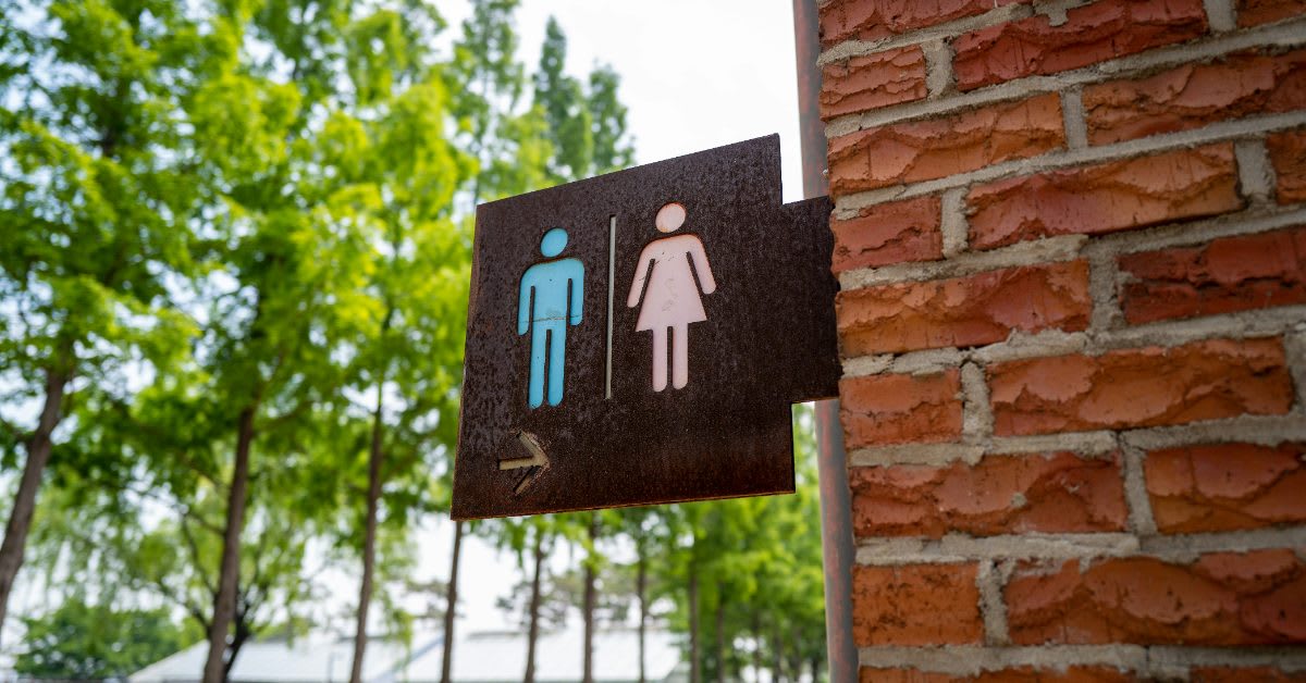 Gender neutral restroom sign mounted on wall in public facility