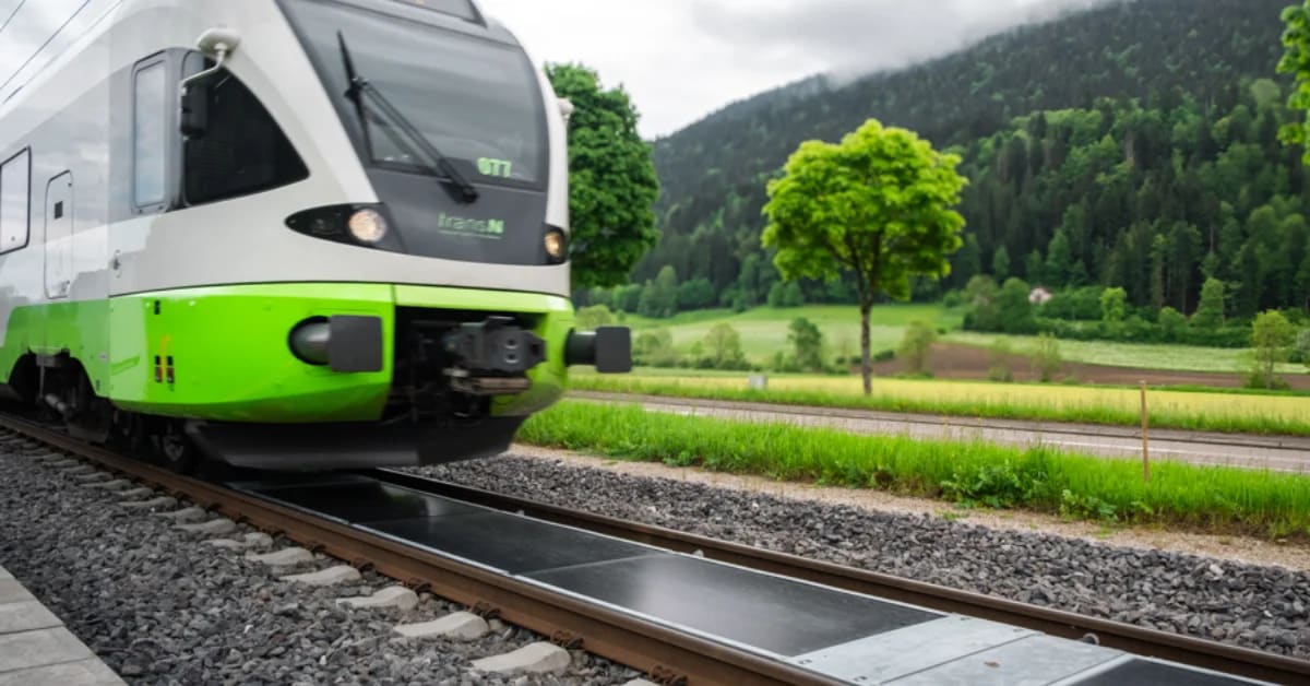 Solar panels installed between active railway tracks with train passing overhead in Switzerland