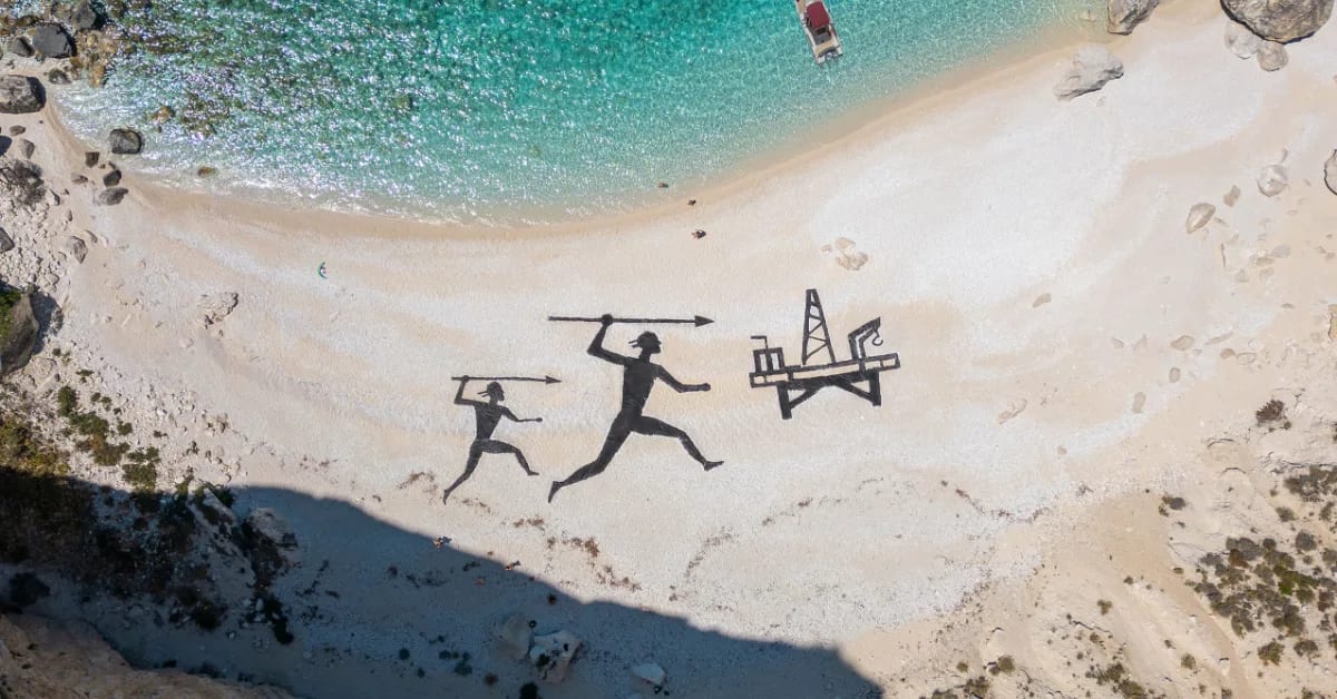 Large-scale beach art showing hunters with spear aimed at offshore oil platform on Greek coastline