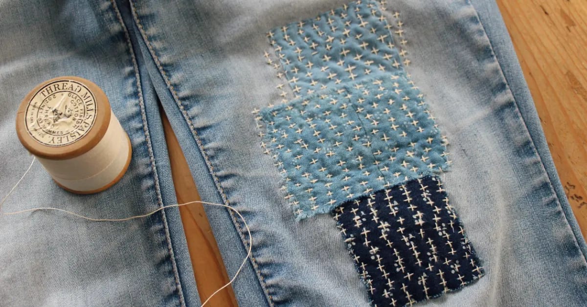 Colorful embroidery stitches repairing torn denim fabric using visible mending technique