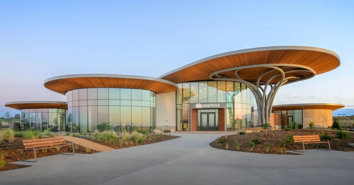 Modern library building with large windows surrounded by open green space in Colorado