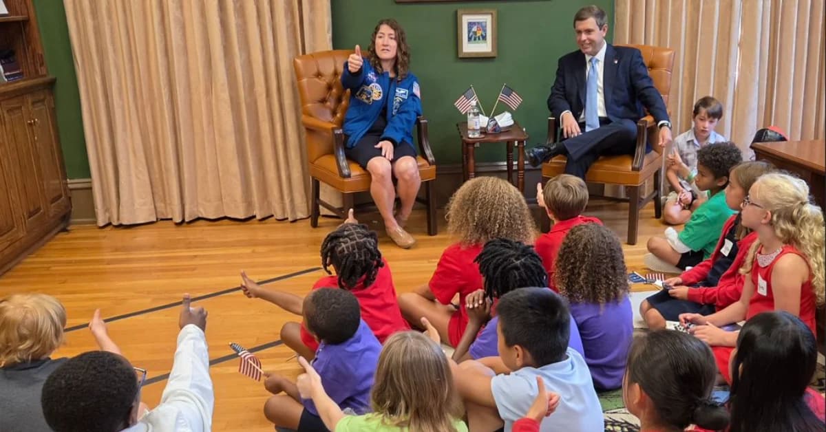 NASA astronaut Christina Koch in flight suit greeting elementary school students at award ceremony