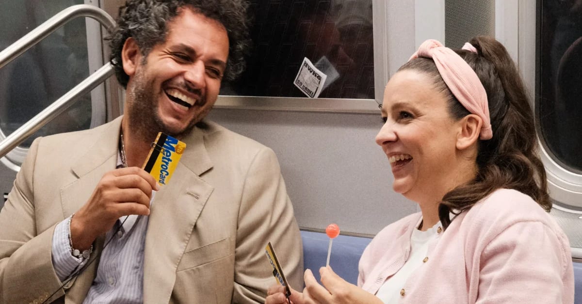 Ms. Rachel wearing pink cardigan and headband speaking on New York City subway train