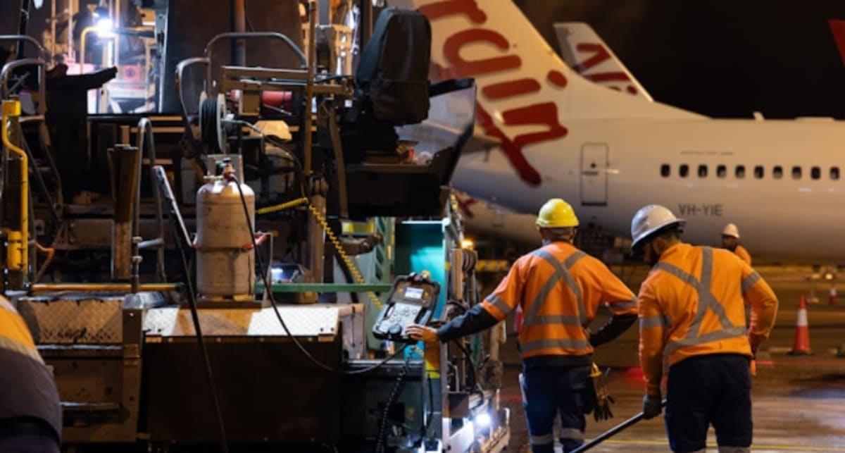 Construction cranes raising steel beams at busy O'Hare International Airport construction site
