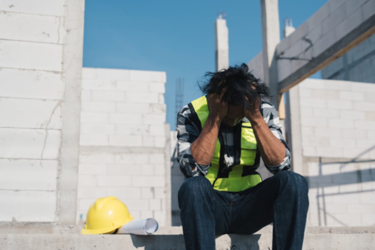 Construction workers wearing hard hats gathered together discussing mental health and recovery support