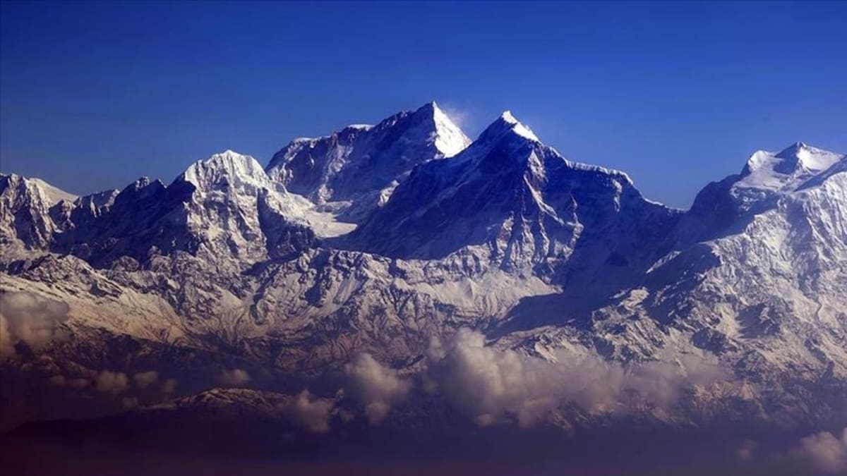 Snow-covered peaks of Mount Everest against clear blue sky showing challenging climbing terrain