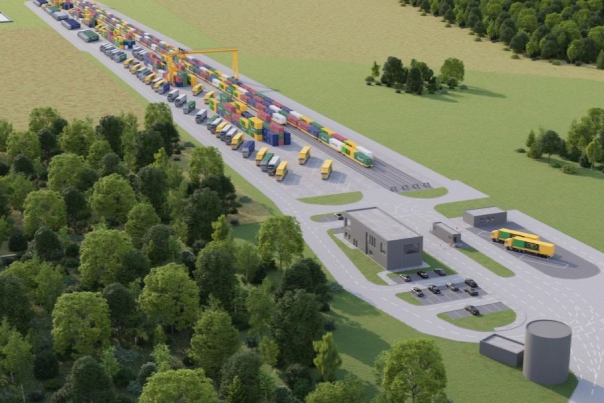 Modern intermodal rail terminal with electric cranes transferring shipping containers between trains and trucks