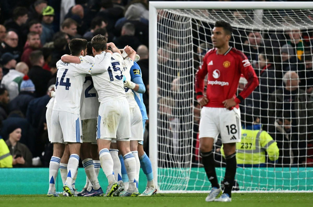 Leeds United players celebrating together after historic victory at Manchester United's Old Trafford stadium