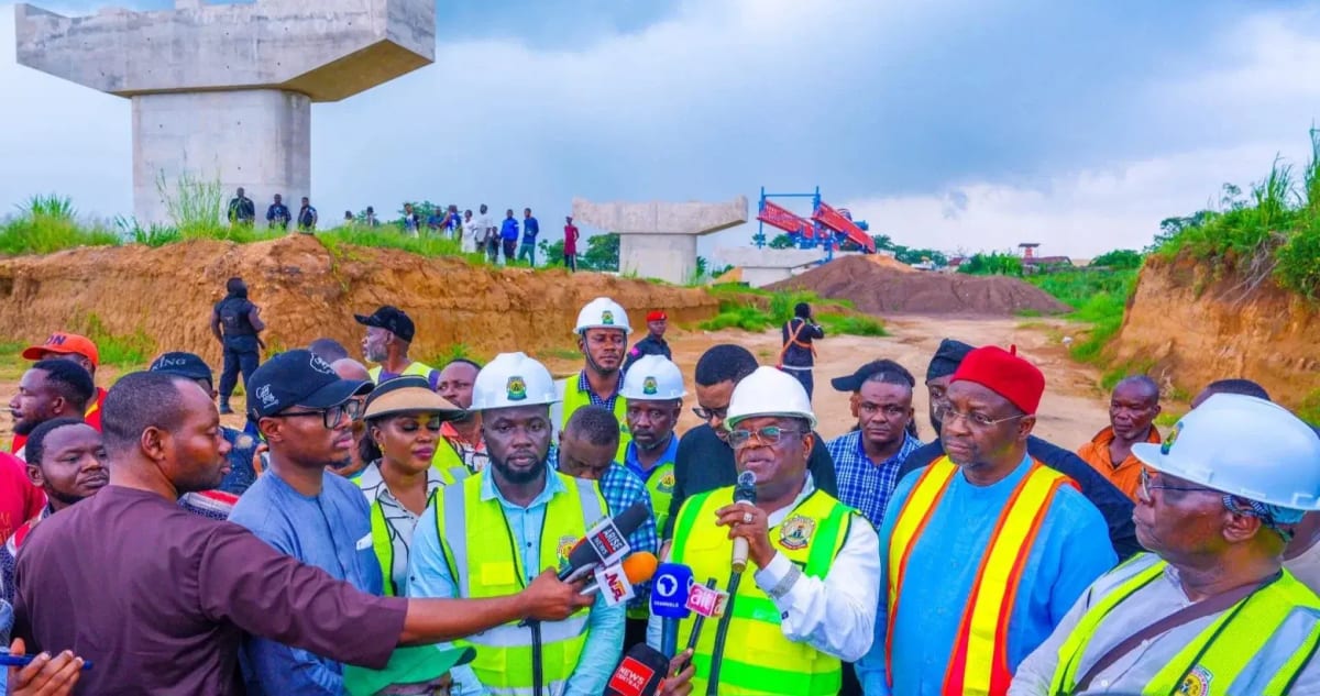 Construction workers building concrete highway section through southeastern Nigeria's green landscape