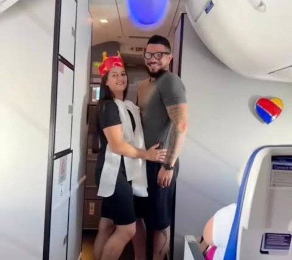 Couple exchanging wedding vows in airplane aisle surrounded by celebrating passengers