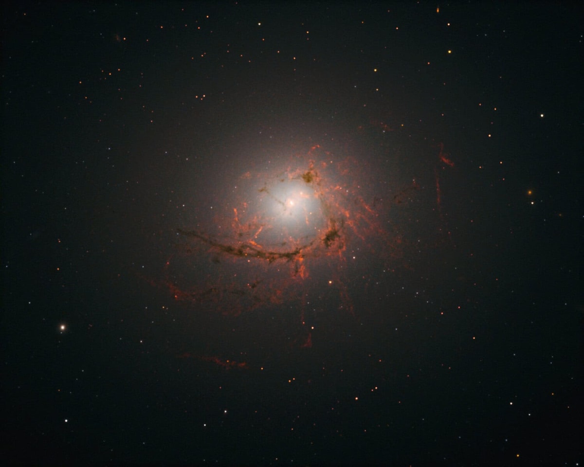 Infrared image showing swirling gas spiraling toward supermassive black hole center in galaxy NGC 4696