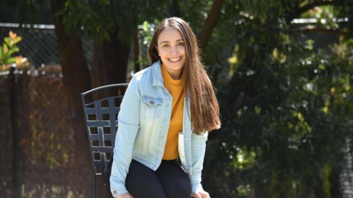 Young woman smiling hopefully as medical researchers examine gut microbiome samples in laboratory