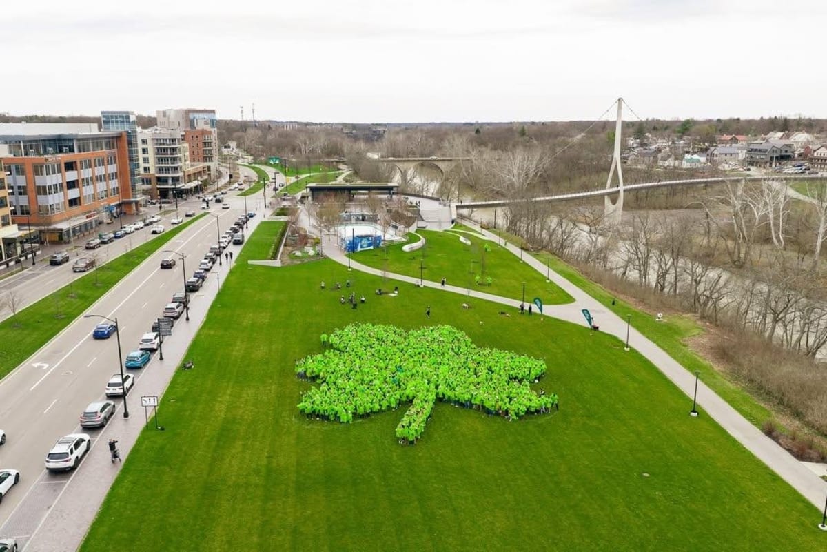 Aerial view of over one thousand people in green ponchos forming giant shamrock shape in Ohio park