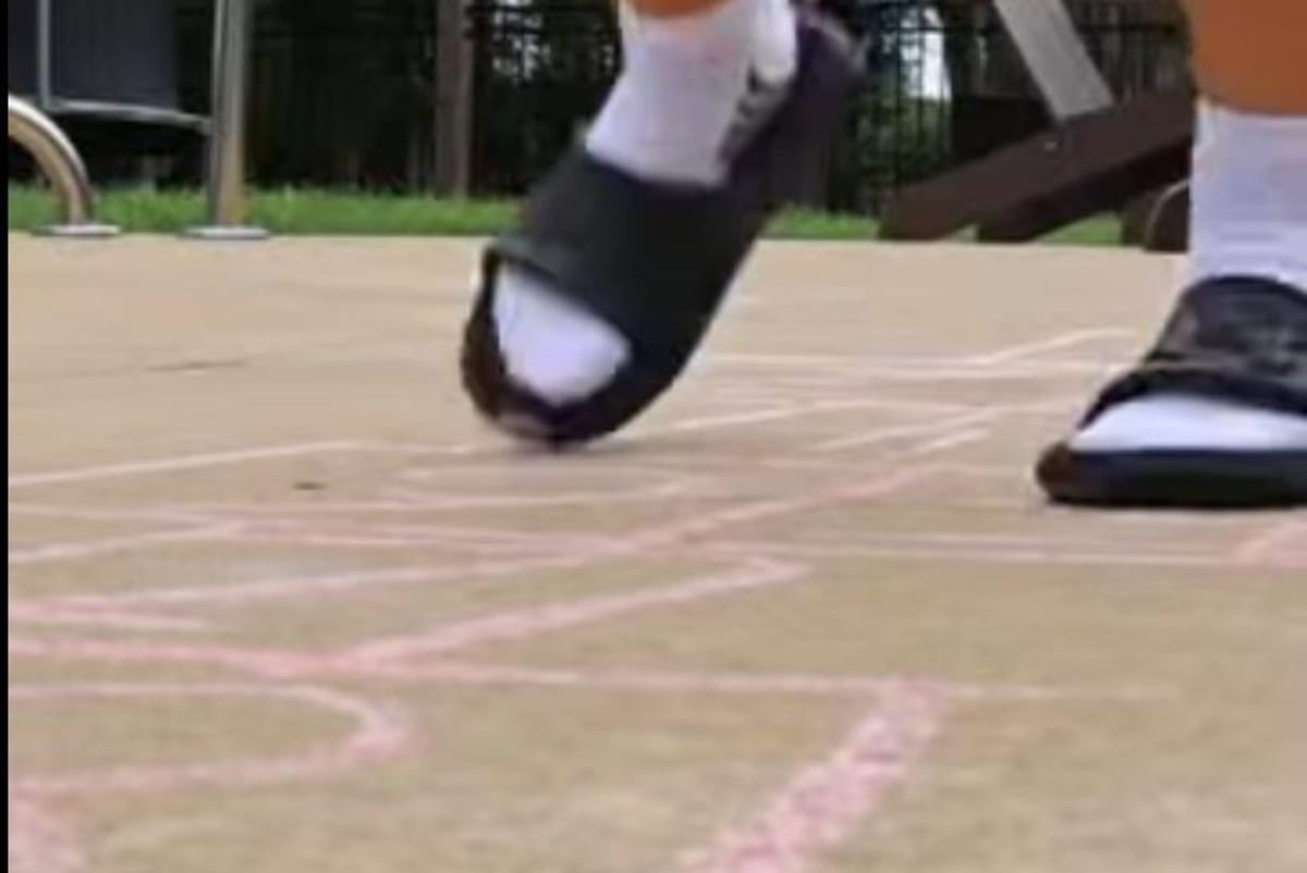 Young boy drawing hopscotch squares with chalk on pavement in Bowling Green Kentucky