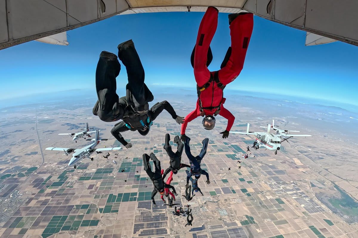 Multiple colorful parachutes filling a bright blue sky during World Skydiving Day record attempt