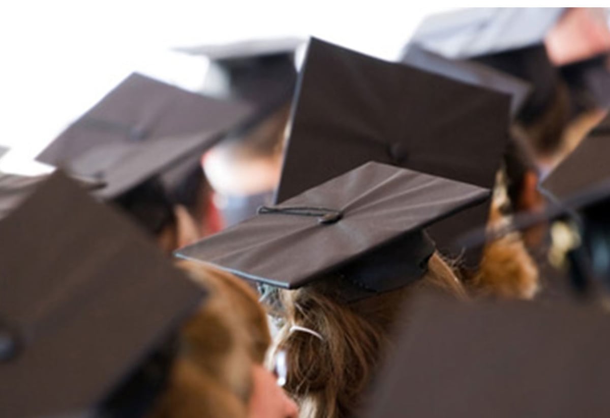 Happy high school graduates tossing mortarboards in celebration of scholarship awards