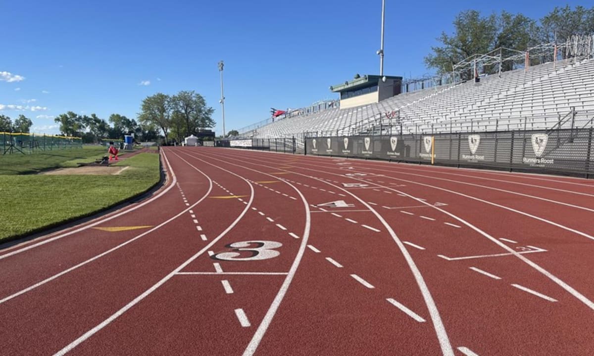 ** High school track athletes racing on outdoor stadium track during Colorado state championship competition