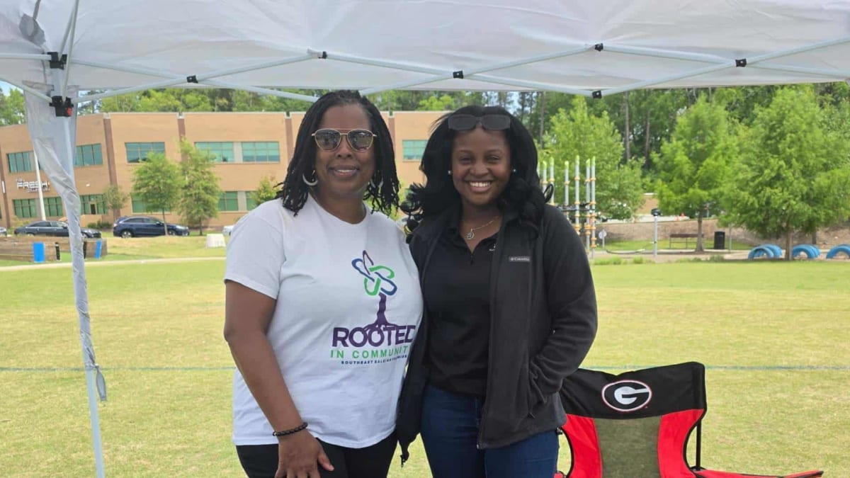 Community members gathered at outdoor Juneteenth celebration discussing electric vehicle information at tables