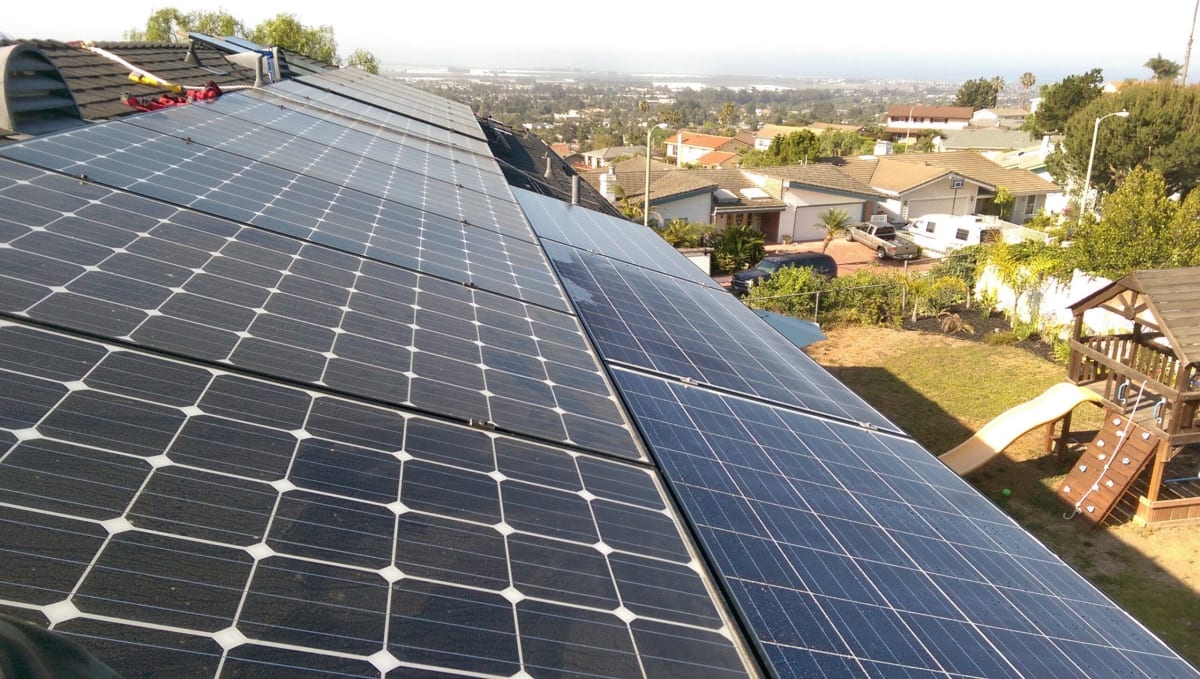 Modern home with rooftop solar panels covering residential roof in bright sunlight