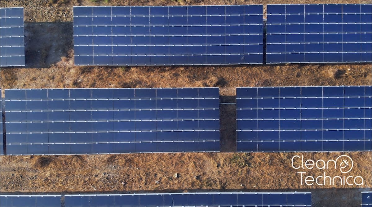 Solar panel array installation on bright sunny day with workers on utility-scale clean energy project