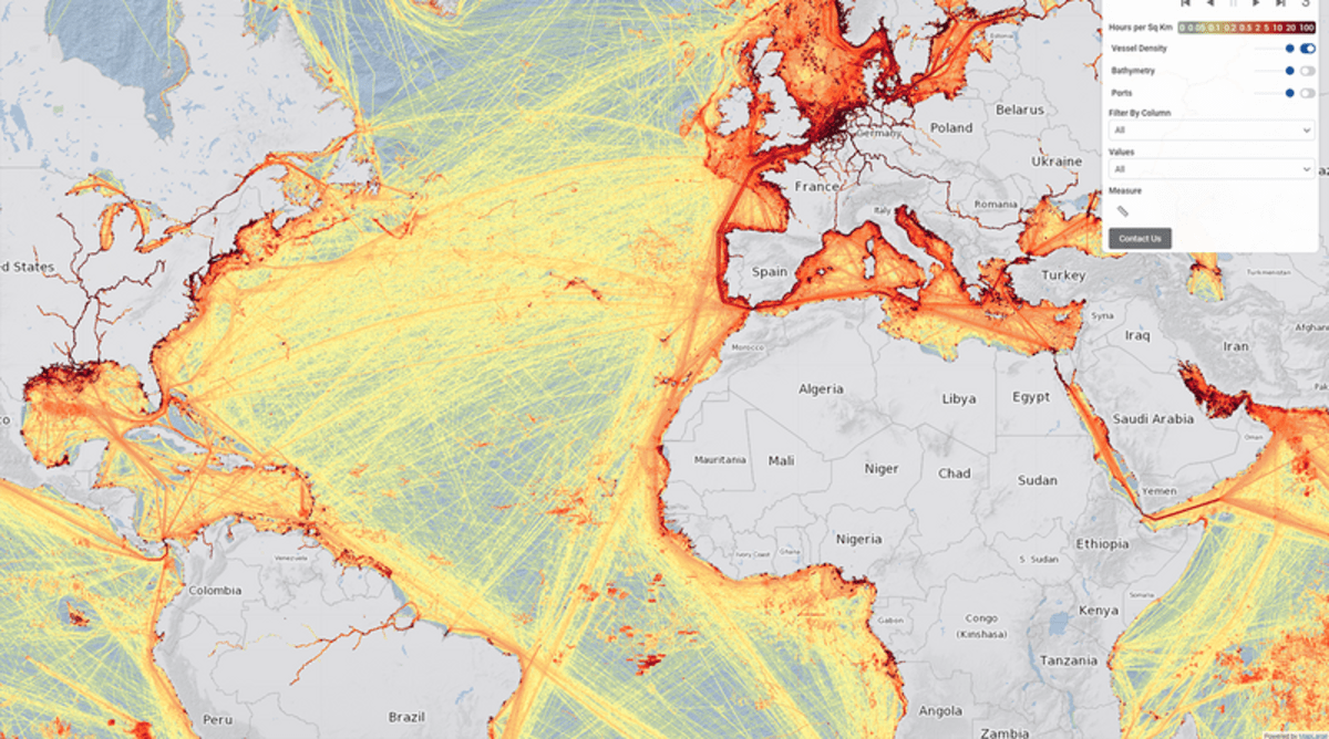 Large container cargo ship sailing across ocean with battery storage containers visible on deck