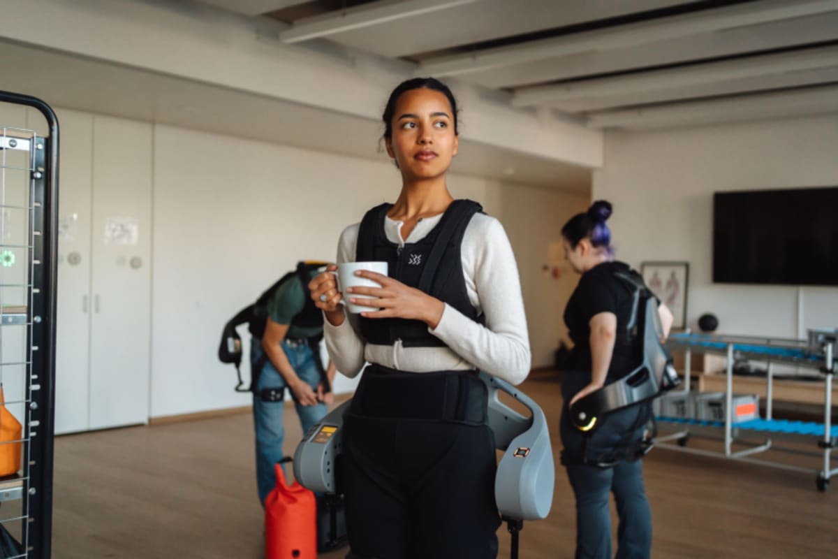 Worker wearing German Bionic Exia powered exoskeleton lifting heavy equipment at renewable energy facility