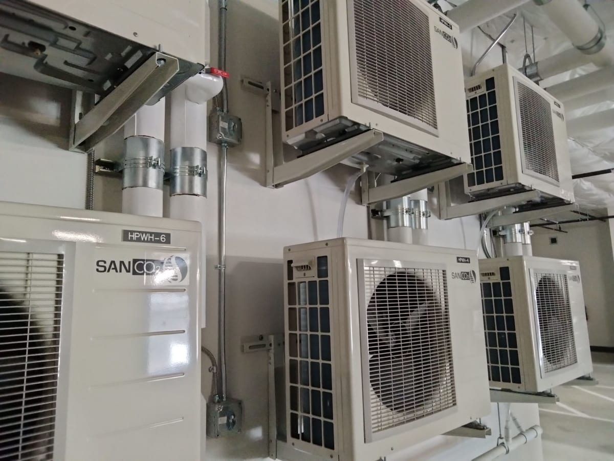 Compact split system heat pump water heater with outdoor compressor unit and indoor storage tank