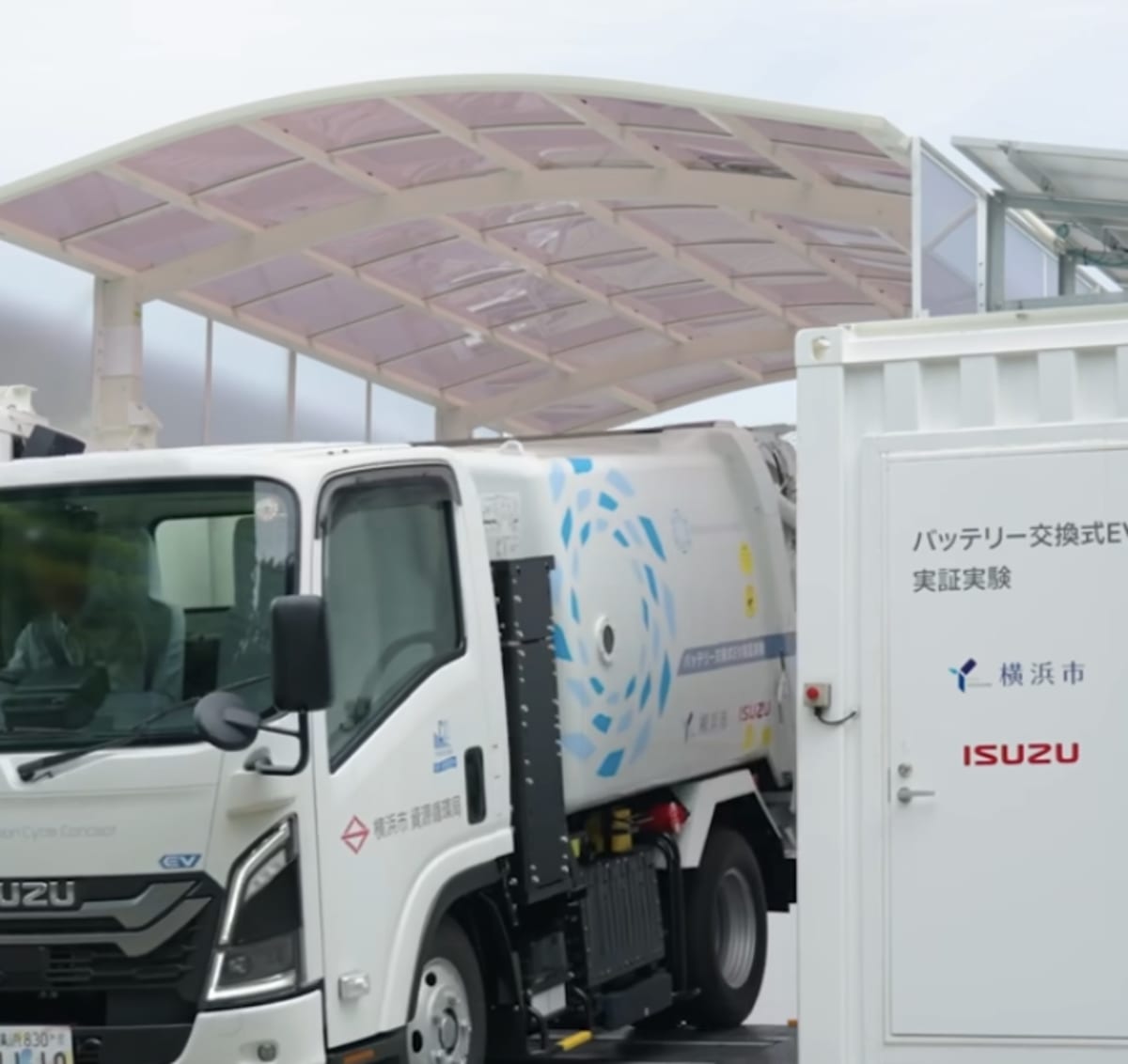 Robotic battery swapping station exchanging power pack on white Isuzu electric garbage truck in Yokohama