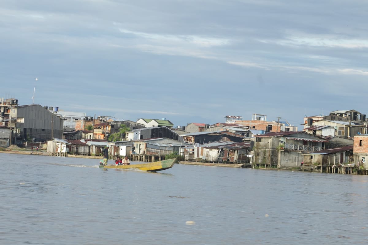 Colombian families walking through a vibrant neighborhood street showing economic recovery and community life