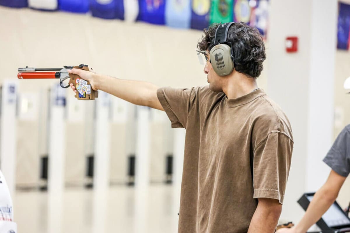 High school senior Ammar Bagasra aiming air pistol at Junior Olympics competition
