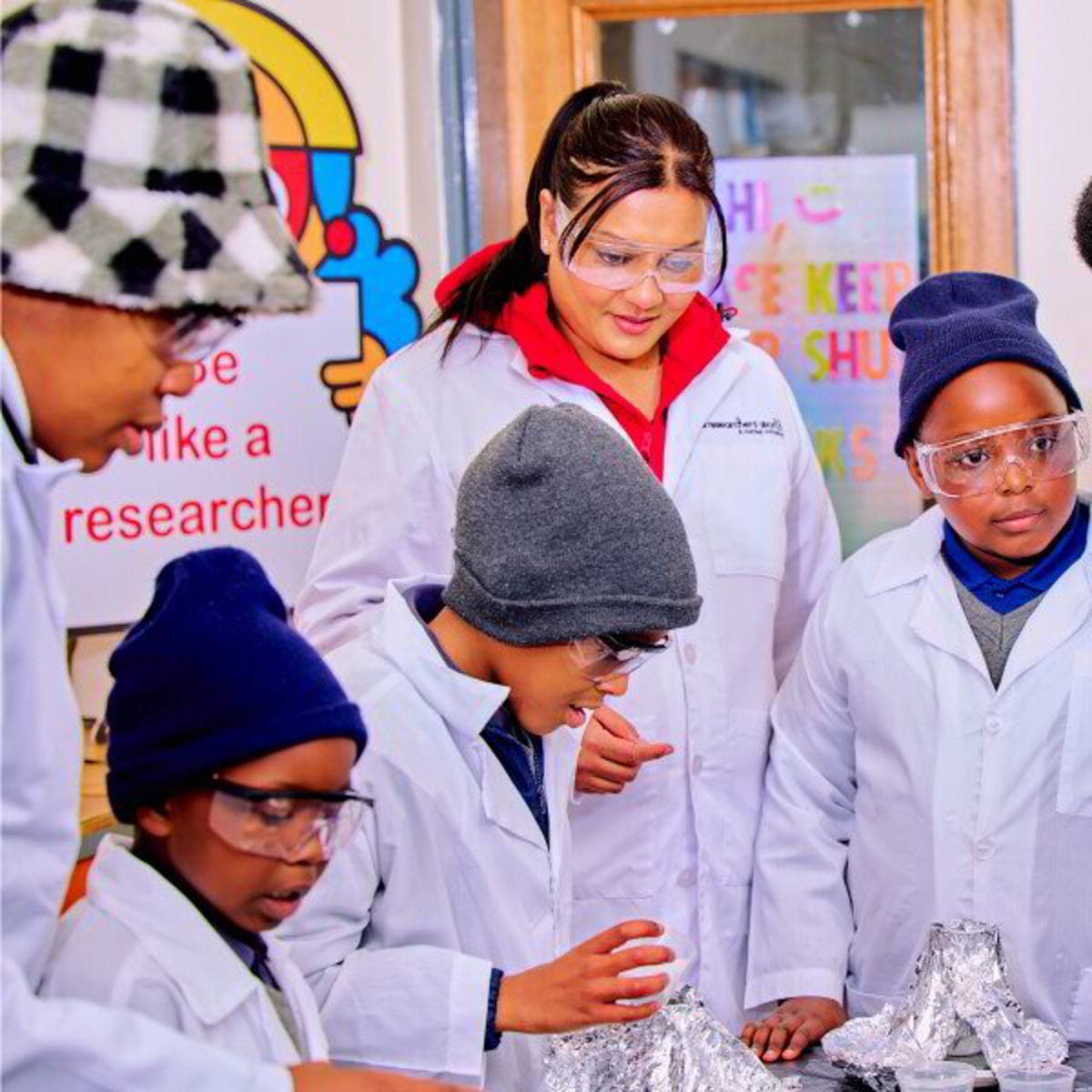 Young students in Johannesburg conducting colorful hands-on science experiments with adult volunteers guiding them
