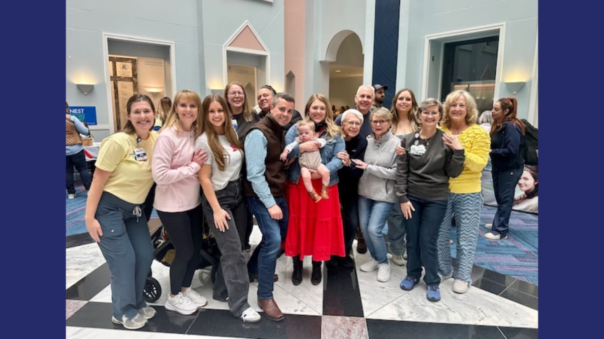 Young boy playing outdoors with parents who smile at medical staff during hospital reunion