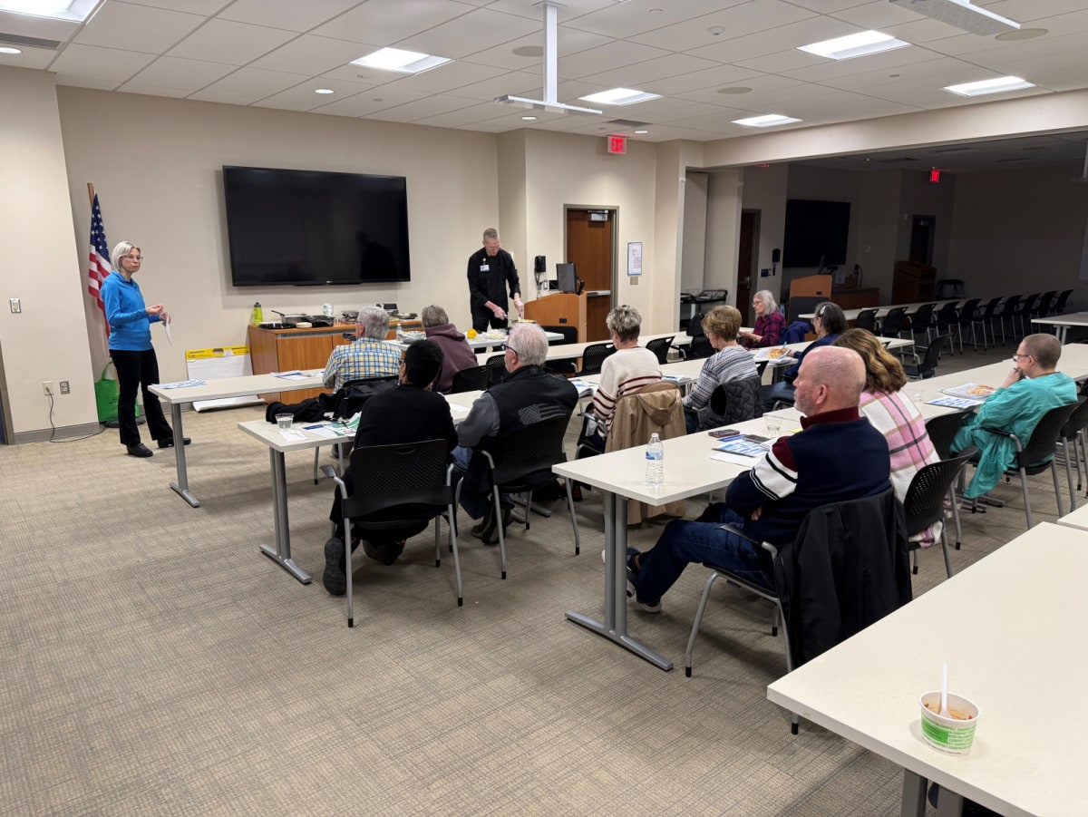 Chef demonstrating healthy cooking techniques to cancer survivors in hospital kitchen classroom