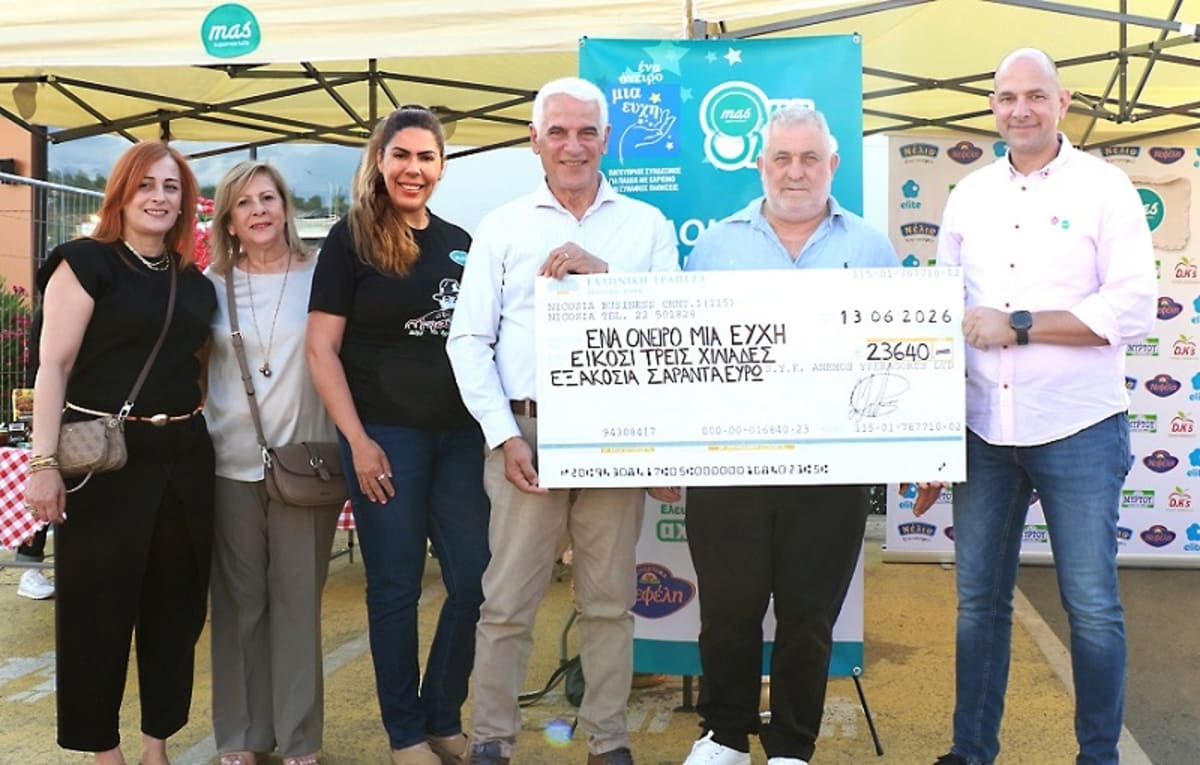 Large ceremonial check presentation at community celebration event with families gathered around