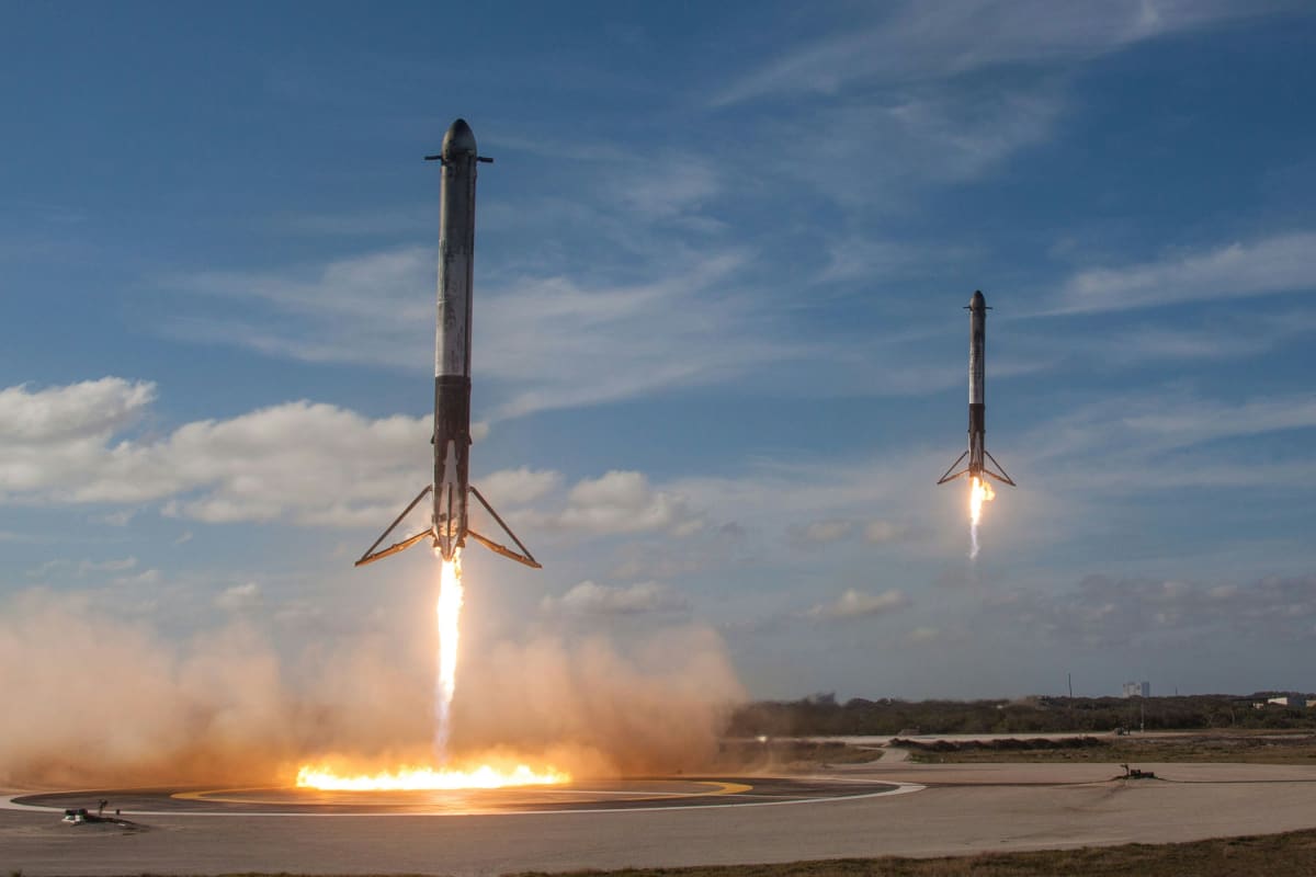 SpaceX Falcon Heavy rocket landing with visible exhaust plumes against blue sky