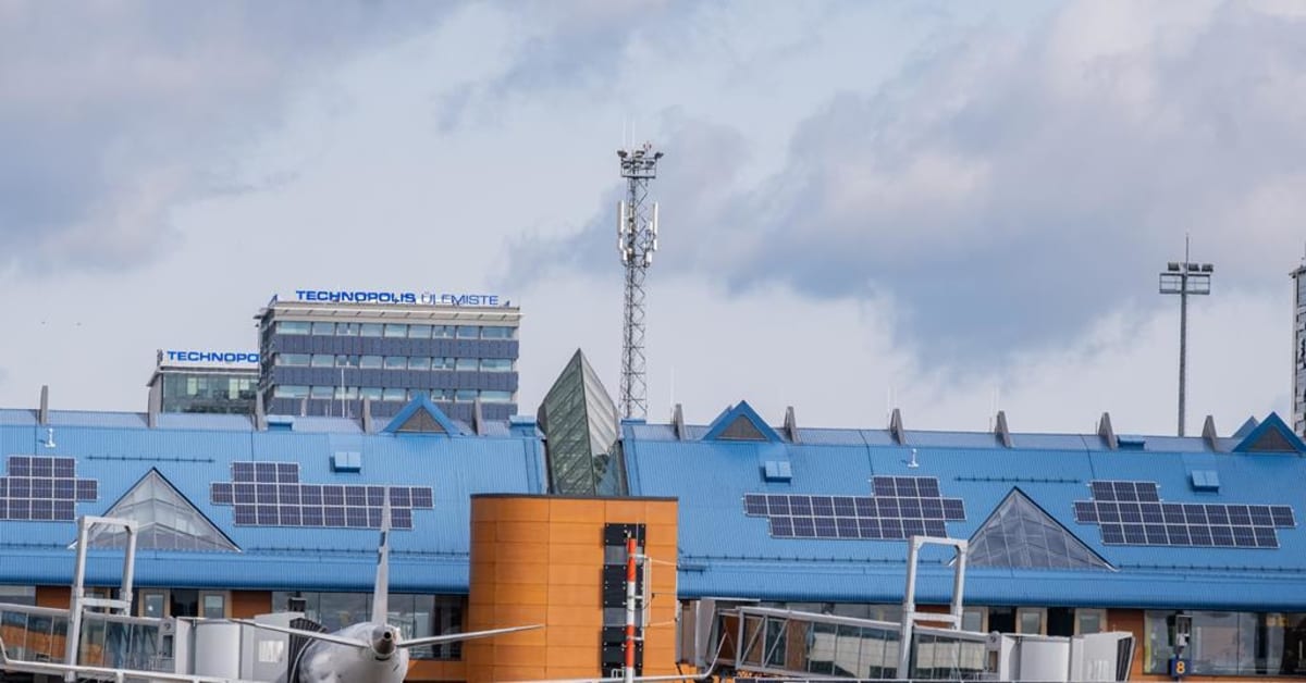 ** Electric ground handling equipment operating quietly on Tallinn Airport apron with solar panels visible on terminal roof