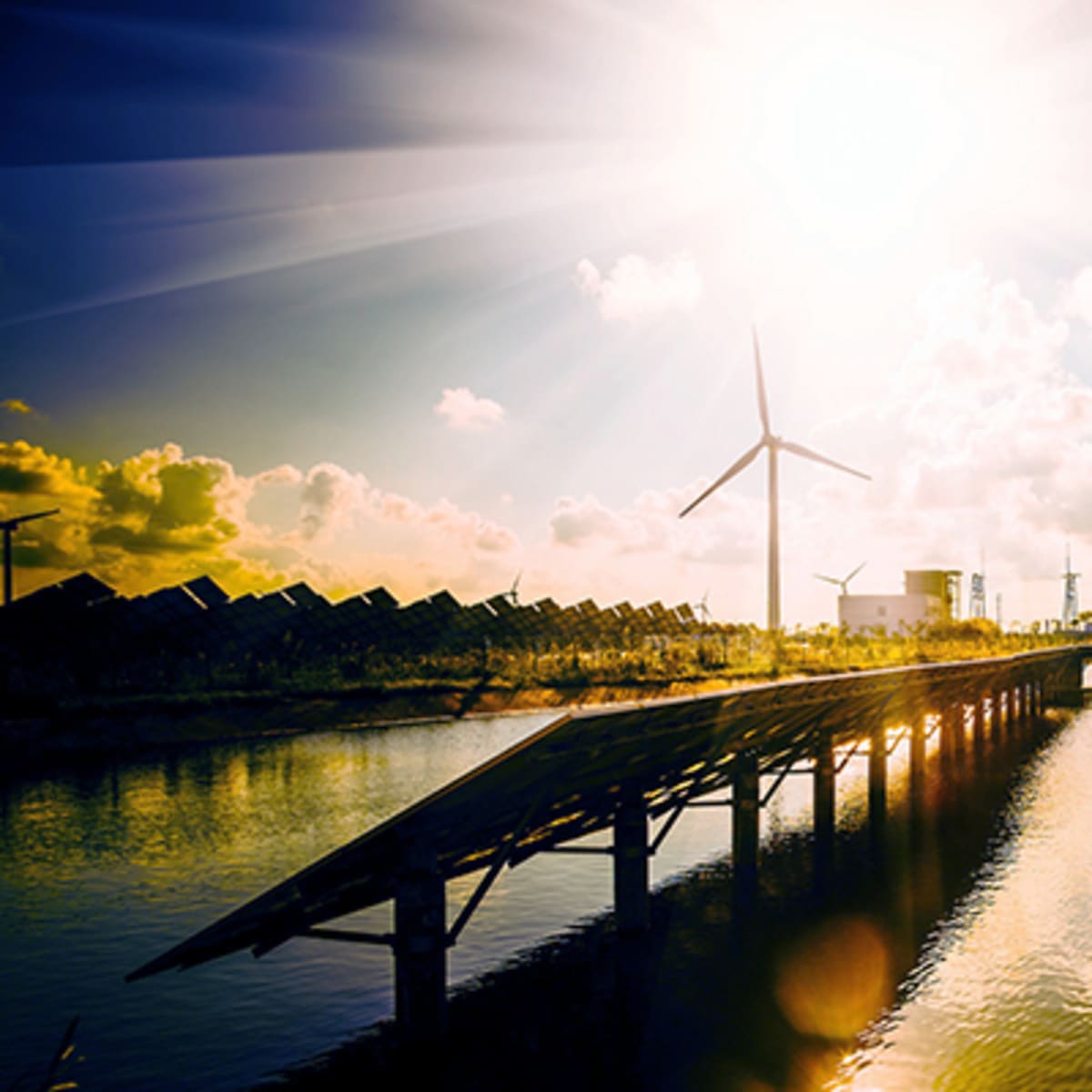 Modern wind turbines and solar panels across European countryside under bright blue sky