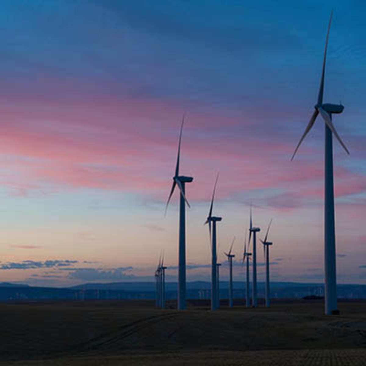 Modern white wind turbines spinning against blue sky in German countryside landscape