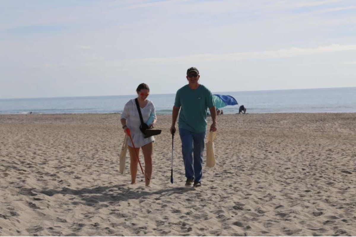 Students wearing school colors clean beach with reusable supplies at Kure Beach, North Carolina