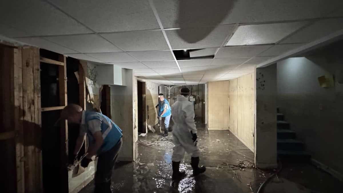 Volunteers in protective gear cleaning flood-damaged home interior in Cadillac, Michigan